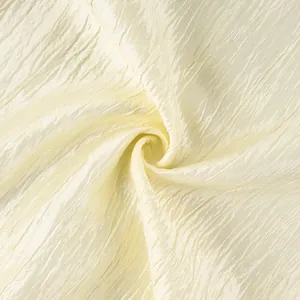 Macro view showing the elegant light cream pleated fabric texture of the lantern pants.