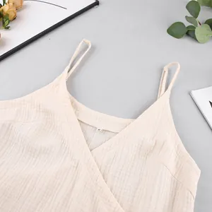 Detailed macro shot of the V-neckline and crinkled gauze cotton fabric on a beige camisole dress.