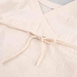 Detailed macro view of cream cotton crepe gauze fabric with a delicate tie-front bow
