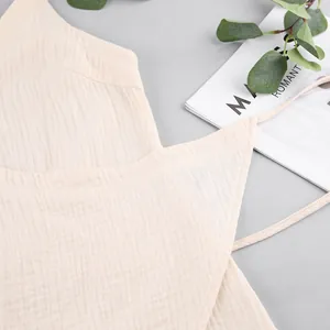 Detailed view of the soft muslin cotton fabric texture on a beige camisole dress.