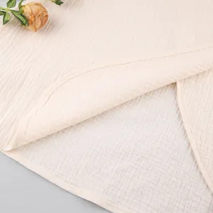 Macro detail of the soft crinkled cotton gauze fabric and stitched hem of the dress