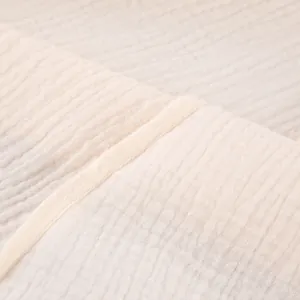 Close-up of cream pure cotton crepe fabric showing the fine texture and seam detail