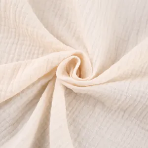 Macro detail of soft beige pure cotton gauze fabric with natural crinkle texture.
