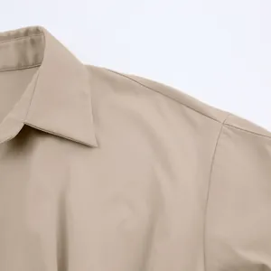 Detailopname van een beige overhemdjurk met kraag en schouderstiksels