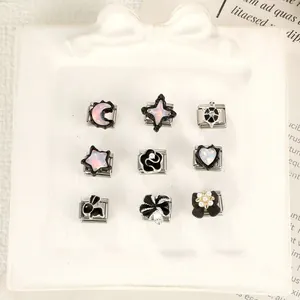 Detail shot of various Italian modular bracelet charms in black enamel on a white tray.