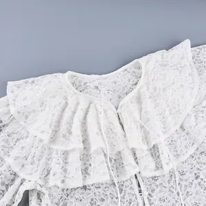 Detailopname van een witte kanten blouse met een dubbellaagse ruffelkraag design