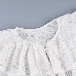 Detailopname van een witte kanten blouse met een delicate dubbellaagse ruffelkraag.