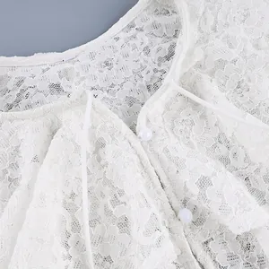 Detailopname van een witte kanten blouse met dubbele ruffelkraag en knoopsluiting.