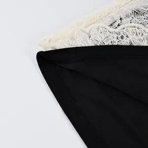 Vista macro dettagliata che mostra il delicato pizzo floreale bianco su un capo nero