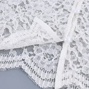 Detailopname van witte kanten blouse met parelknoppen en details van ruches aan de zoom
