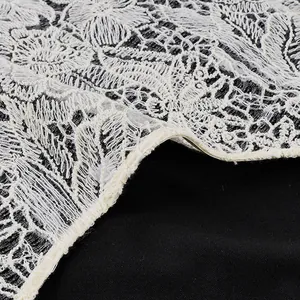 Dettaglio pizzo floreale bianco su tessuto nero per completo due pezzi da donna