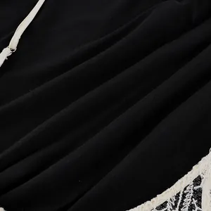 Primo piano del tessuto della camicia nera con eleganti bordi in pizzo bianco e trama fine