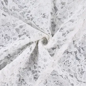 Detailopname van delicate witte bloemenkantstof met een verfijnde mazenstructuur