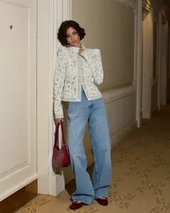 Donna elegante con camicia in pizzo bianco a collo alto in un corridoio dallo stile raffinato.