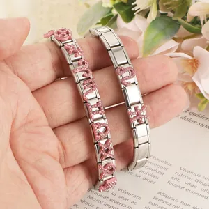 Dettaglio di charm zodiacali in strass rosa su bracciali componibili italiani in acciaio