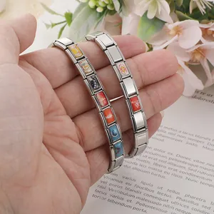 Dettaglio ravvicinato di bracciali modulari italiani in acciaio con charm smaltati colorati.
