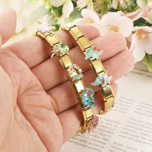 Gros plan d'un bracelet italien modulaire doré avec des breloques papillon colorées