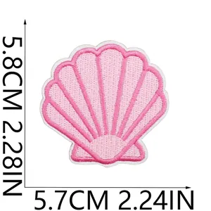 Dettaglio macro di una toppa ricamata a forma di conchiglia rosa con dimensioni.