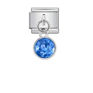 Close-up of a silver Italian charm link with a dangling faceted blue birthstone.
