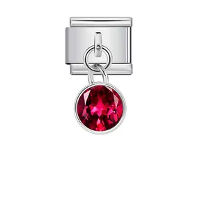 Detailed view of a silver modular charm featuring a dangling round red birthstone gem.