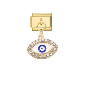 Close-up of golden Italian charm link featuring a rhinestone-encrusted evil eye pendant