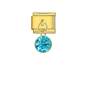 Close-up of gold Italian charm module with light blue dangling crystal pendant.