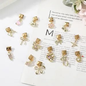 Vue détaillée de divers modules de bracelets à breloques italiens dorés avec touches roses.