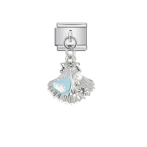 Nahaufnahme eines muschelförmigen italienischen Charms mit blauem Herzstein und einer Perle