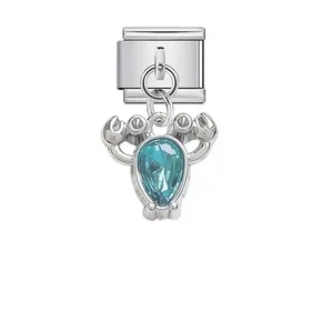 Primer plano de un dije de cangrejo de plata con cristal azul para brazaletes DIY