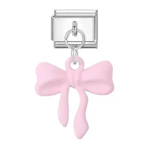 Close-up detail view of a silver stainless steel modular jewelry link with a matte pink bow pendant