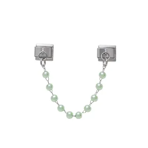 Close-up of a modular stainless steel charm link with a light green pearl chain detail.