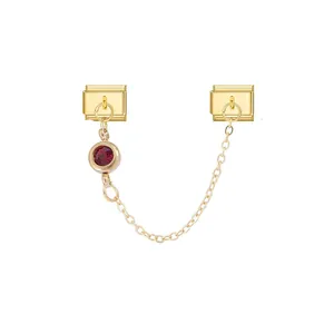 Detail view of a modular jewelry link with a red gemstone on a gold-plated chain.