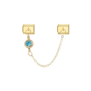 Detail of modular gold charm with light blue crystal and connecting chain for DIY bracelets.