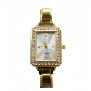Close-up of a gold square quartz watch with rhinestone border and silver dial.