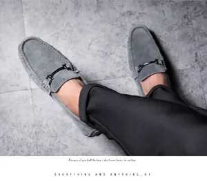Close-up of stylish grey suede loafers for men featuring a dark metal buckle detail