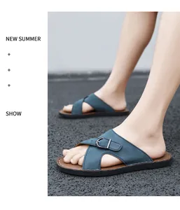 Detailed view of men's blue slide sandals featuring an adjustable buckle on asphalt.