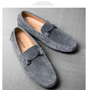 Close-up of grey suede men's loafers with metallic bit detail on a textured floor