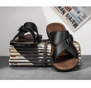 Detailed shot of black faux leather cross-strap men's sandals with buckle on newspapers