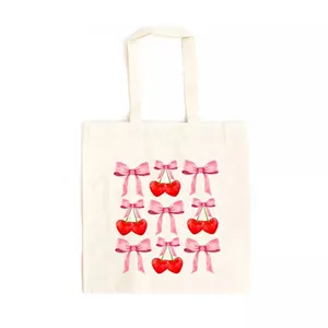 Cream canvas tote bag featuring a sweet watercolor pink bow and red cherry print detail