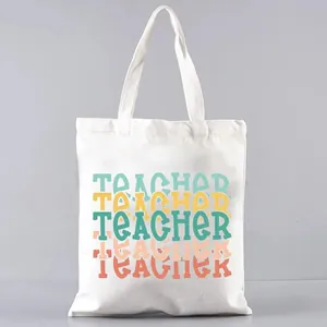 Detailed close-up of a white canvas tote bag featuring colorful printed Teacher text