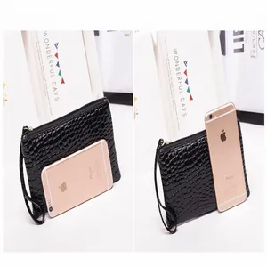 Gedetailleerde vergelijking van een zwarte clutch met krokodillenprint en telefoon.