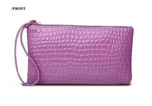 Front view detail of a stylish purple crocodile embossed leather clutch bag with wrist strap