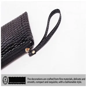 Vista detallada de un bolso de mano negro con motivo de cocodrilo y asa de mano.