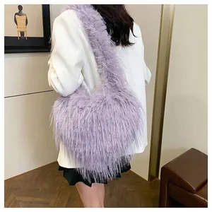 Close-up detail of a trendy purple heart-shaped faux fur shoulder bag with long fringes.