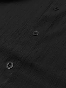 Detailed macro shot of black textured men's casual shirt fabric and buttons.