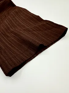 Macro detail showing the rich ribbed texture of dark brown fabric on a men's casual shirt