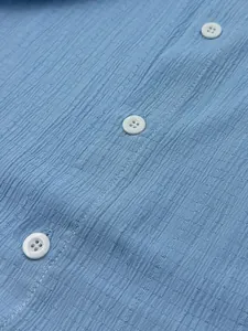 Close-up of light blue textured fabric on men's casual shirt with white buttons