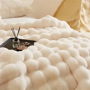 Gros plan d'une couverture en fausse fourrure à bulles blanches dans une chambre douillette.