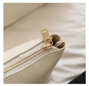 Detaillierte Nahaufnahme hochwertiger goldener Reißverschluss-Hardware an beiger Tasche.