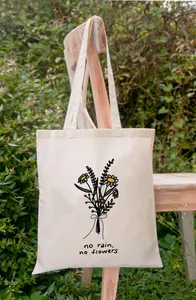 Detailweergave van de No Rain No Flowers bedrukte canvas draagtas in een tuinsetting